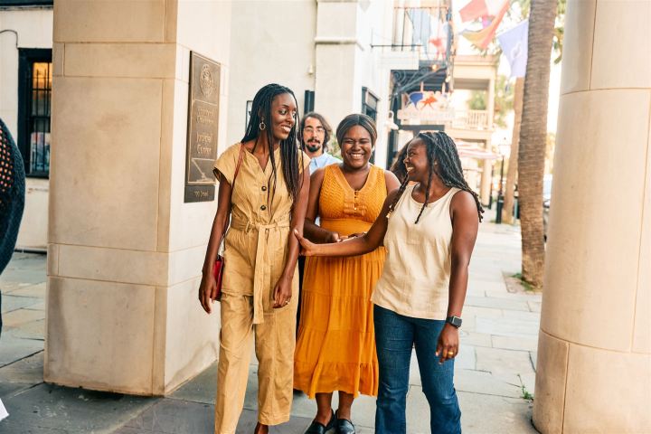 Group of four friends smiling and talking while walking in a city street.