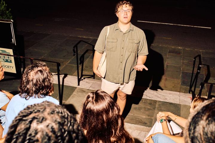Person speaking to a small group on outdoor steps at night.