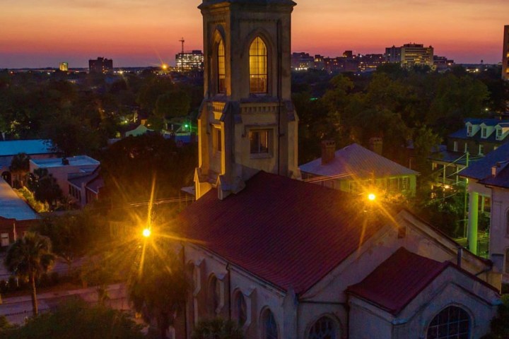 a large clock tower towering over a city at sunset