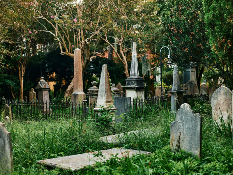 Old cemetery with overgrown grass and various gravestones.
