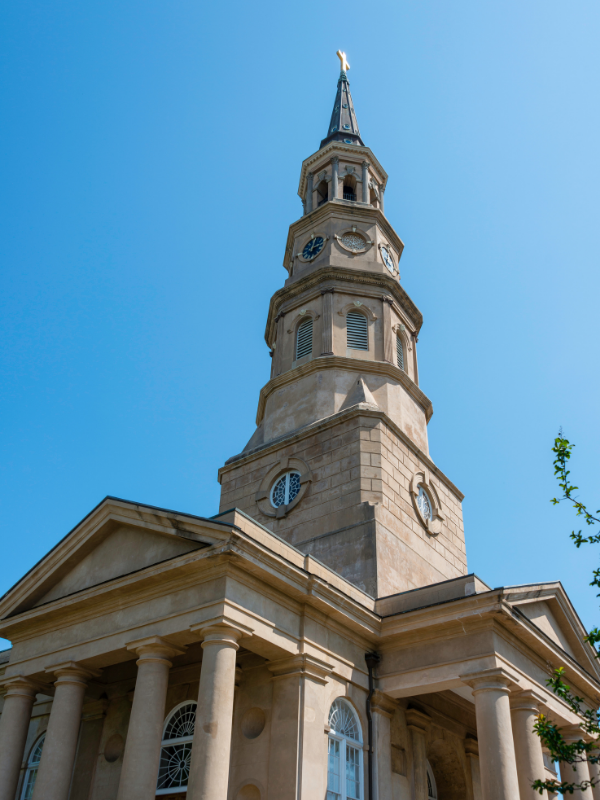 Tall stone church steeple with clock and blue sky.
