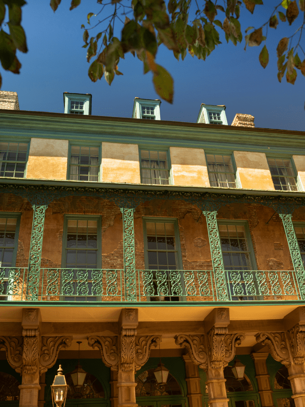 Historic building with ornate balconies and green trim against a clear sky.
